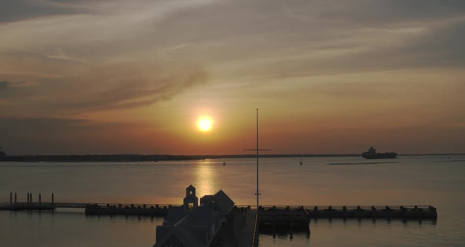 Aerial view of a pier next to the ocean at sunset