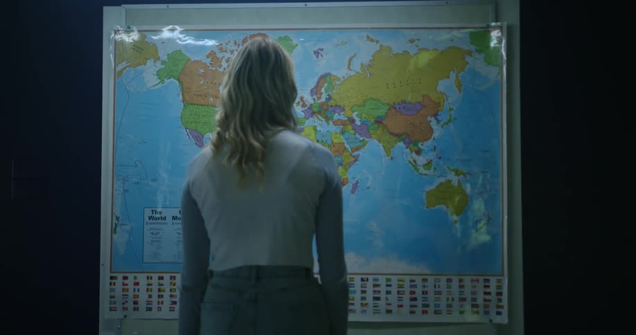 A woman stands and looks at a large map on the wall