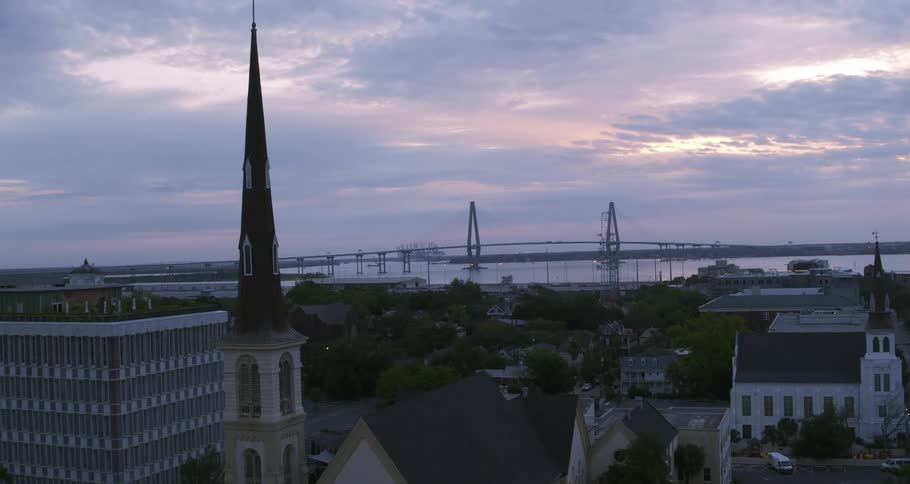 A purple blue sky looms over a city area filled with new and old structures