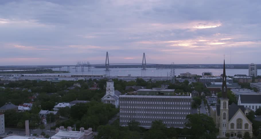 Aerial view of a small waterfront city in front of a bridge over a river at evening