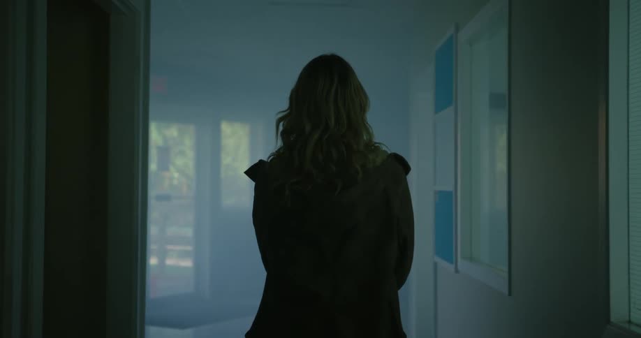 A woman walks down the dark hall