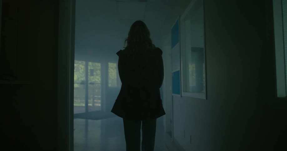 A woman walks in the dark hall