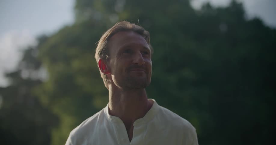 A man smiles as rain falls on his hand