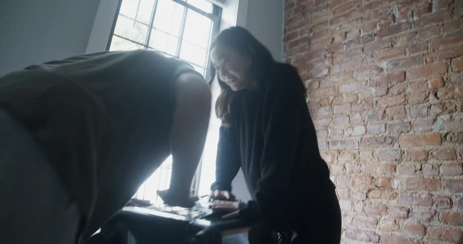 A man and woman pack a suitcase full of clothes
