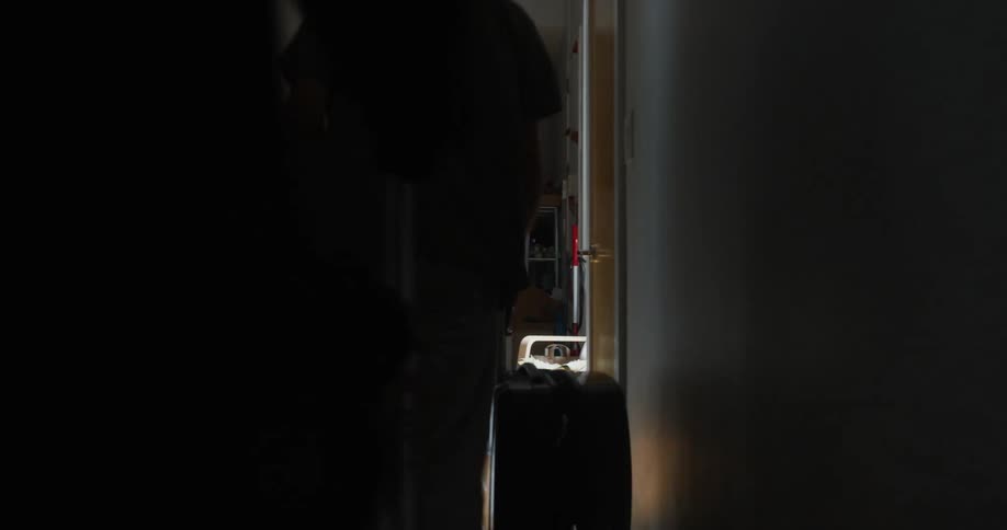Man and woman pull wheeled luggage down hallway in home