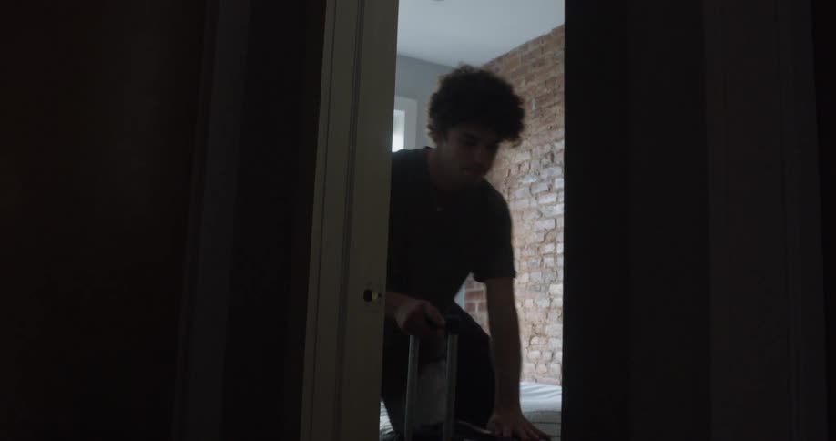 Man and woman place luggage onto floor in bedroom and roll them down hallway