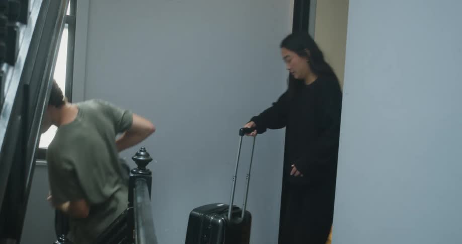 A man and woman carry their luggage down the stairs