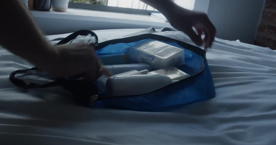 A person packs up toiletries in a small bag