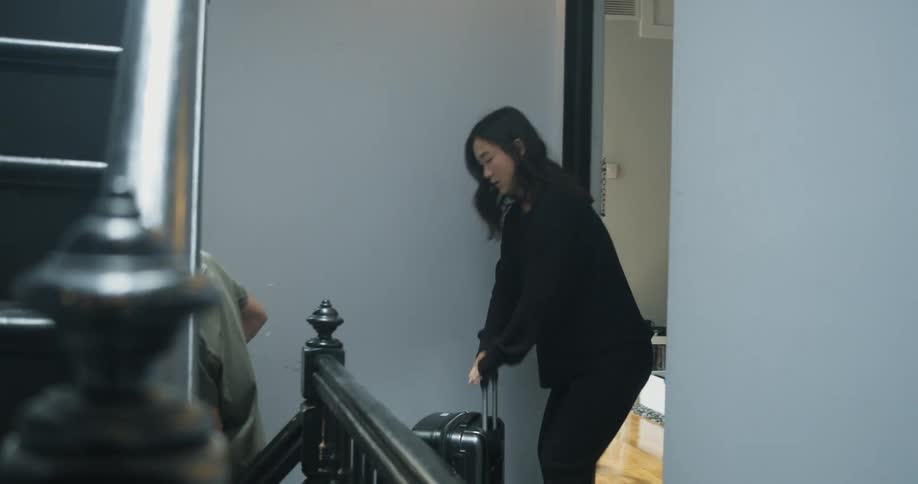 A man and woman carrying suitcases down stairs