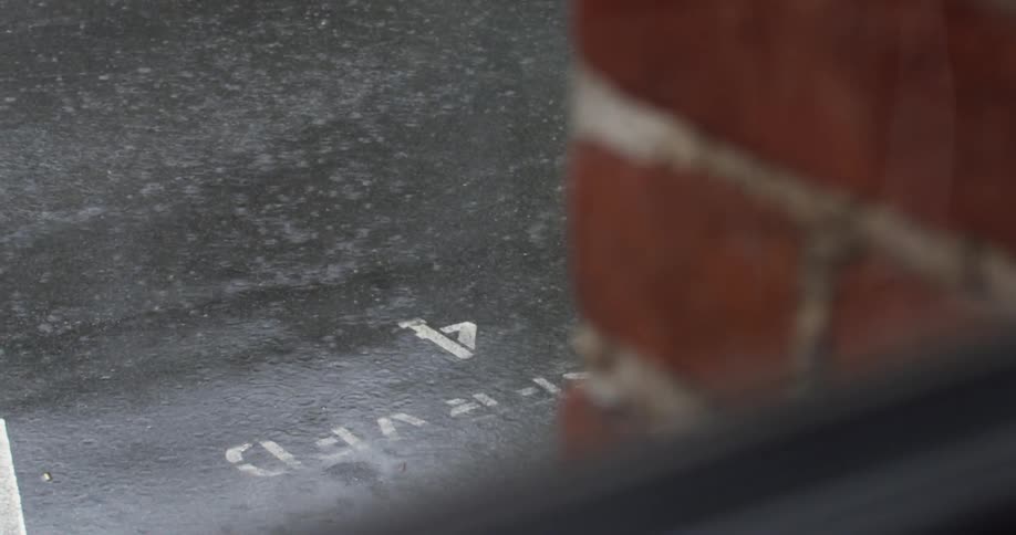 A heavy rainfall is seen hitting the asphalt of a parking lot