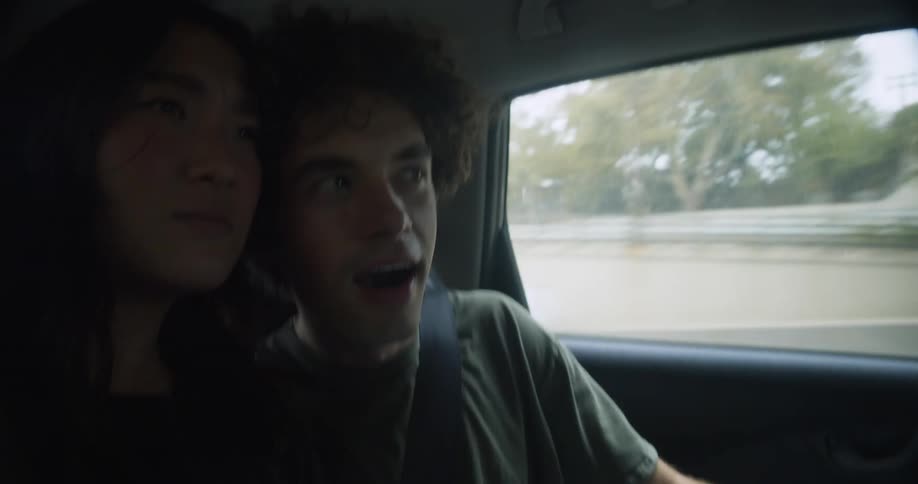 Young couple talking while riding on the backseat of a driving car