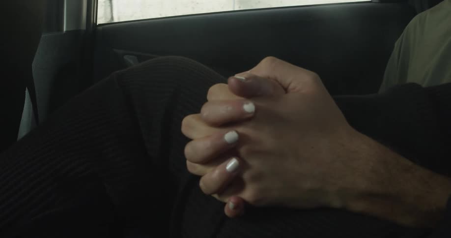 Couple sitting in the back seat of car holds hands