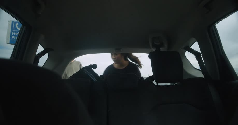Man and woman get out of car rear seat and get their luggage out of back