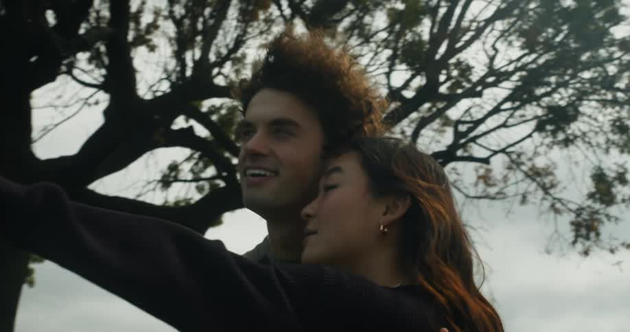 A man hugs a woman as she points at a plane taking off and flying past