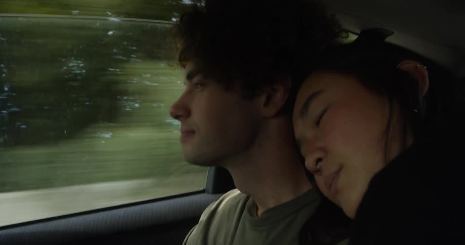 Couple cuddle while sitting in rear seat of moving car