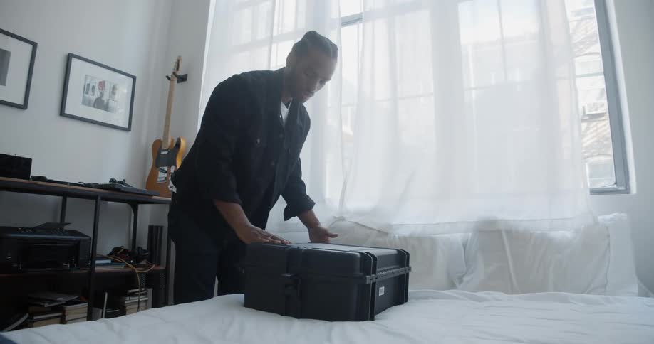 A man packs and closes his suitcase then walks away