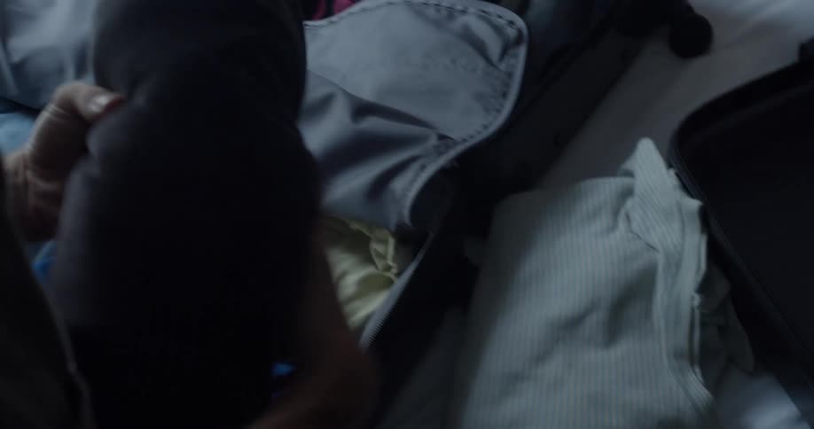 A man is packing his luggage with clothes