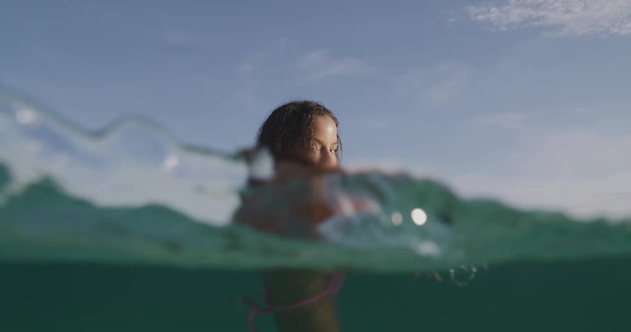 Woman wearing swimsuit wades through clear ocean water
