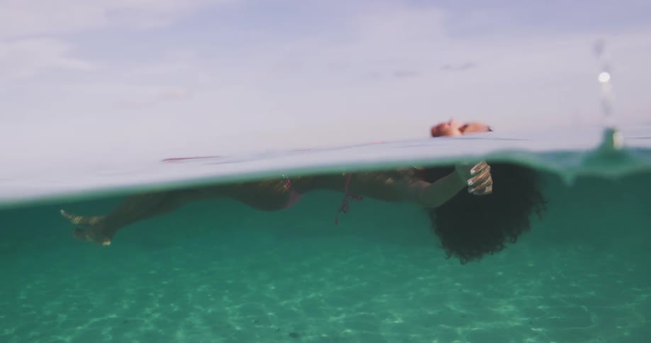 Woman wearing swimsuit floats on clear water under cloudy sky
