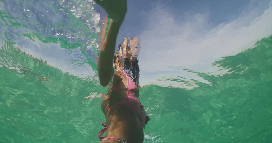 Woman with pink bikini standing in sea seen from underwater