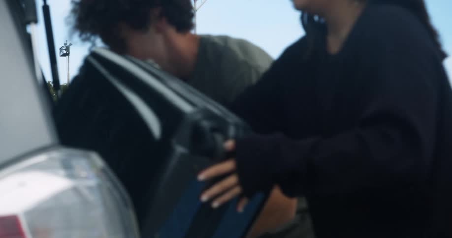 A couple grab their luggage from the vehicle while heading to the terminal