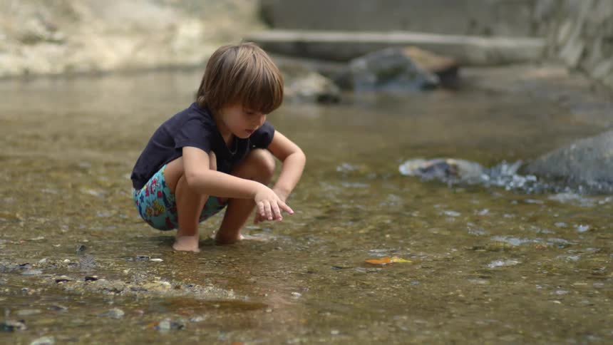 A boy is floating leaves in the stream