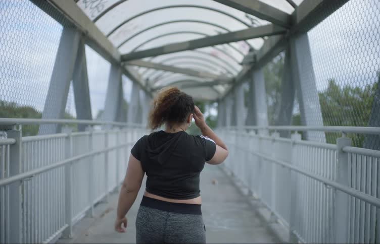 A woman jogging on the overpass takes a break