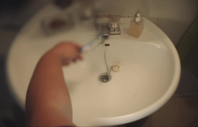A person puts their toothbrush under the water