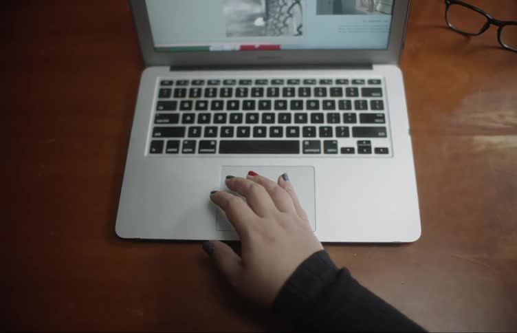 Woman in black sweater using touchpad closes the laptop