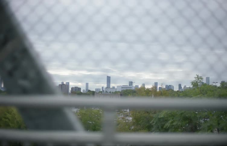 Traveling in a vehicle while crossing a bridge with a metropolis skyline in the background on an overcast day