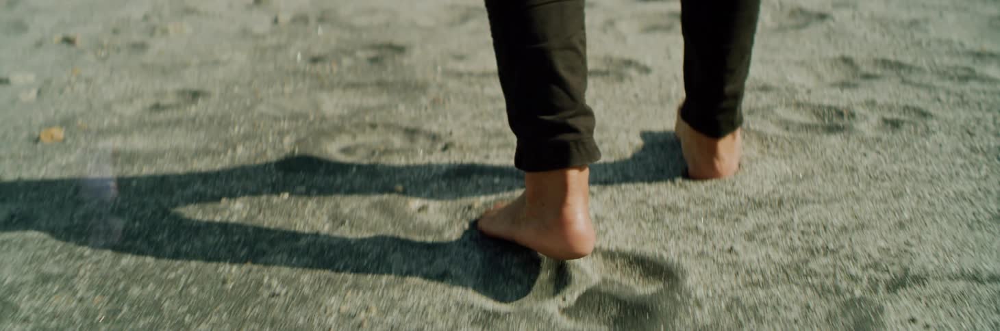 A man walks barefoot on the beach