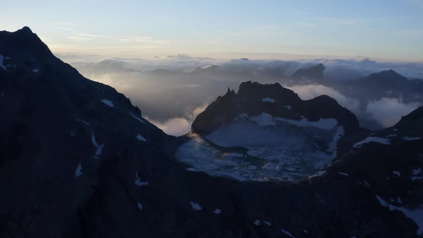 Fog lays low over snow capped mountain peaks