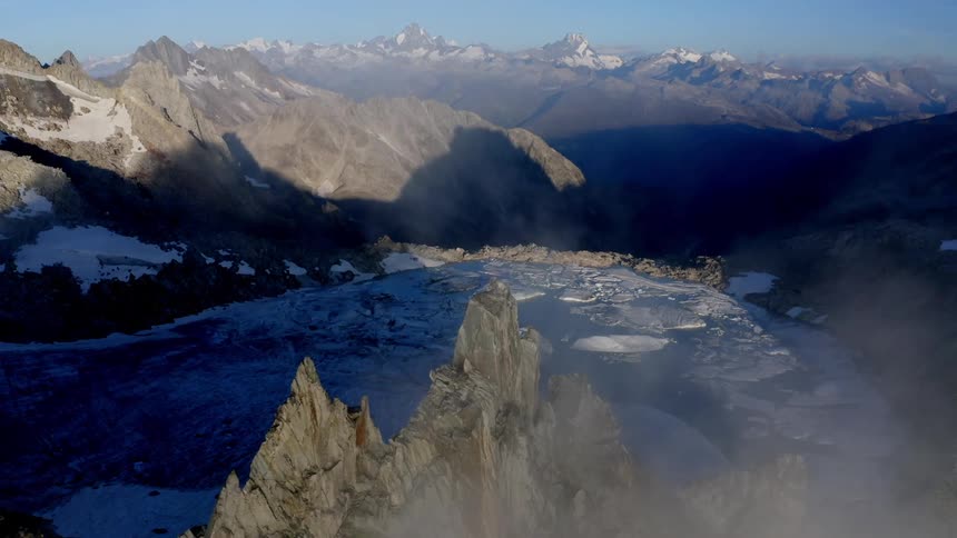 Low lying clouds hover over peak near lake covered in floating ice