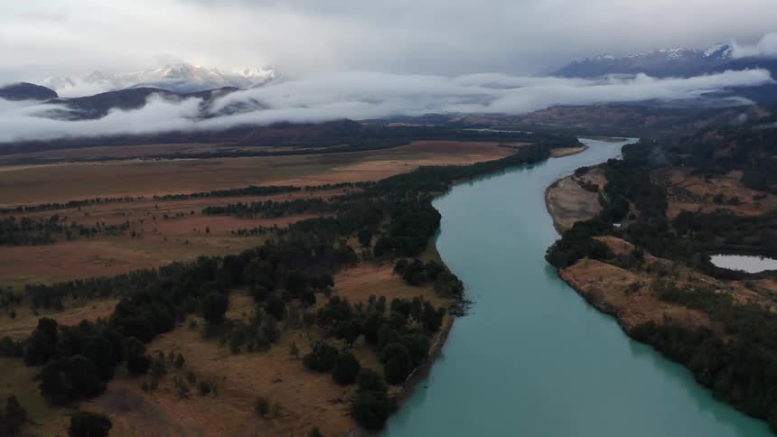 The aqua waters of the Rio Baker in Patagonia Chile with low hanging rain clouds swirling about