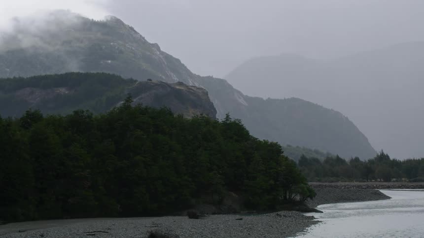 A view of mountains with a river and trees at the base