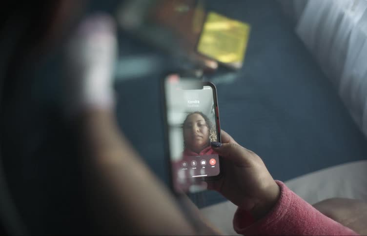 A woman taps video call on her phone and waits on camera for someone to pick up before giving up