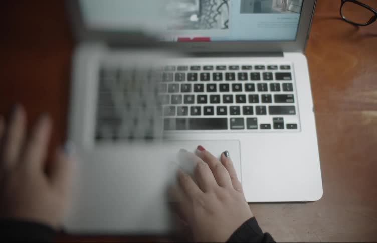Womans hands with colorful nails uses and closes laptop with half blurry screen