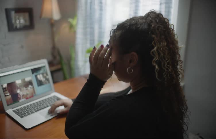 Woman sits at table scrolling images and typing on keyboard
