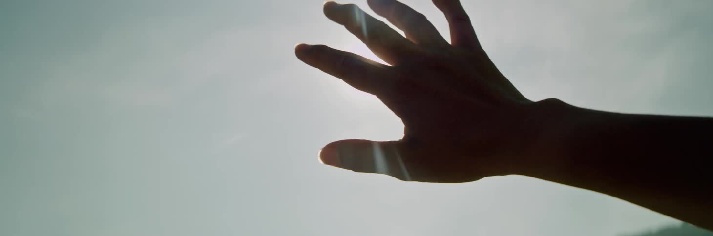 A person holds their hand up to shield the sunlight