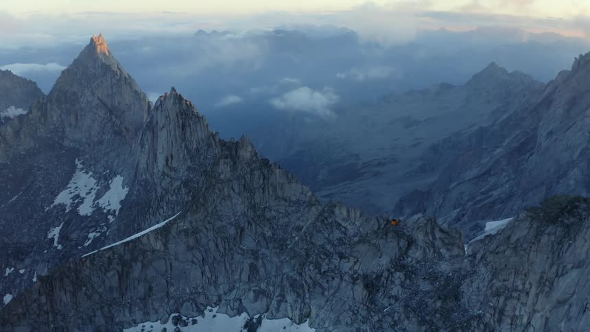 Snow settles on the sides and valley of a steep mountain range