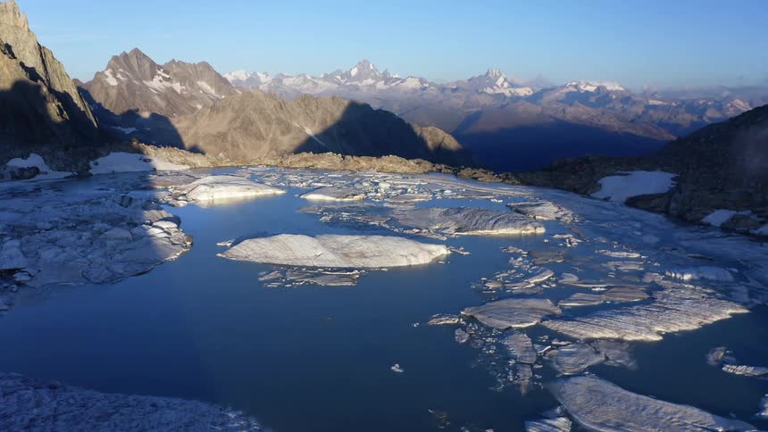 A view of a lake at the top of a mountain with ice in it