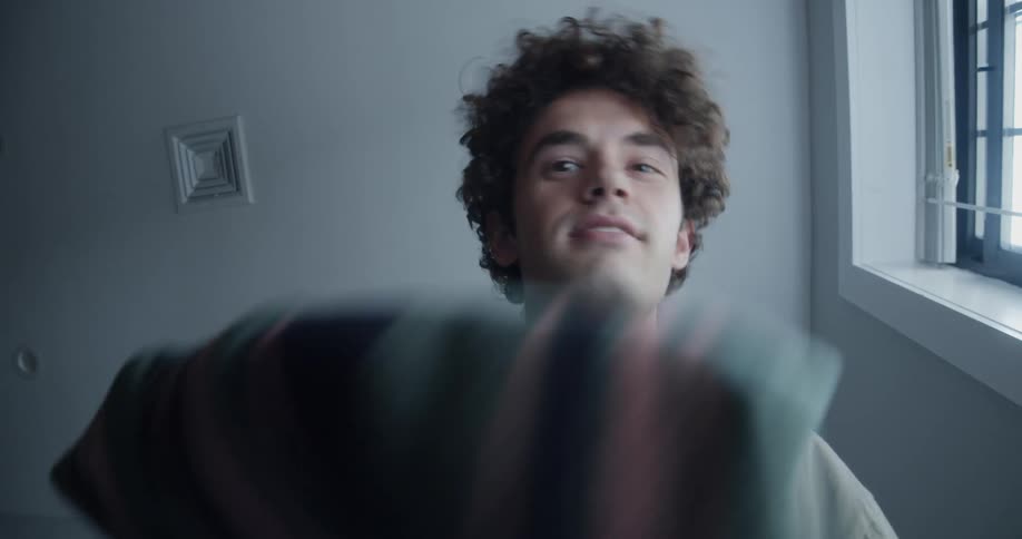 Happy and excited man with curly hair packs his suitcase
