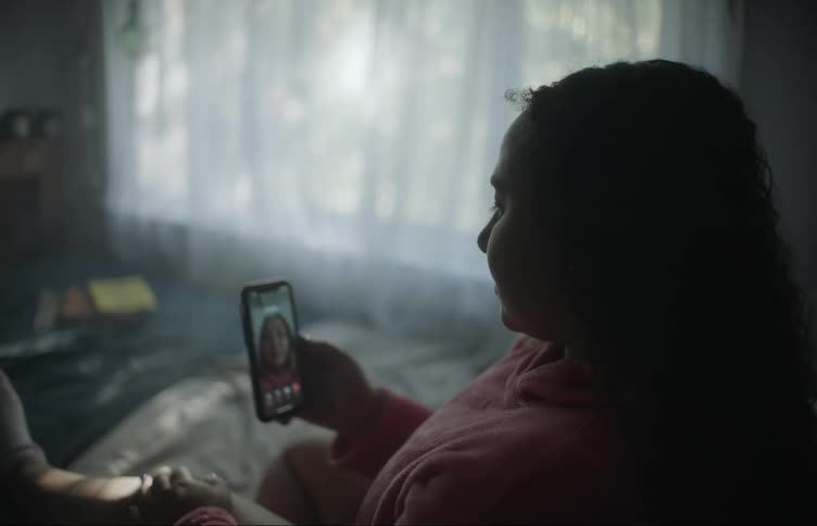 A girl sitting on her bed tries to make a video call but doesnt get an answer