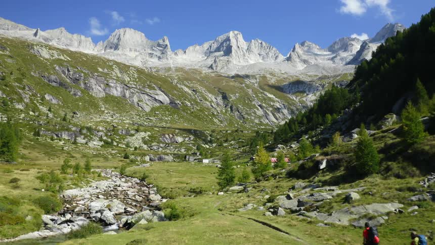 Backpackers hike through a deep valley in a mountain range