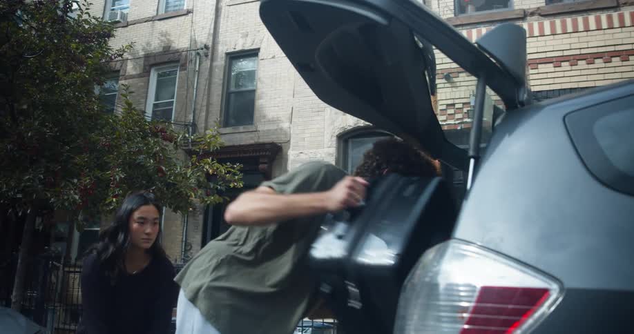 A couple pack luggage into the taxi