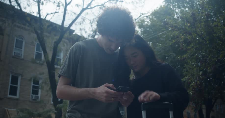 Man and woman stand with luggage consulting mobile phone