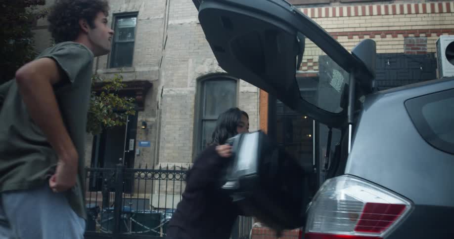 A couple rush to put their luggage in a taxi and leave