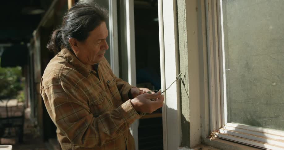 A man tied a rope to his home and is pulling it across his yard