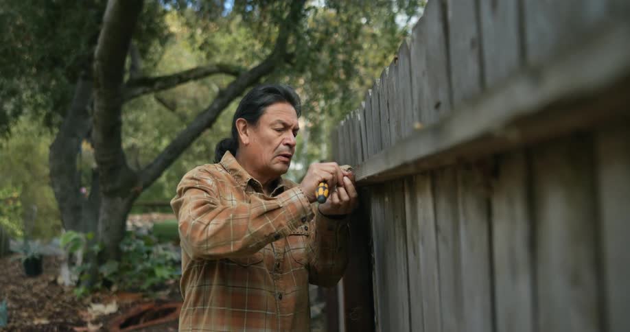 A man is repairing his fence outside