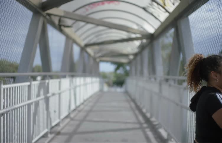A woman walks on the overpass then stops and turns